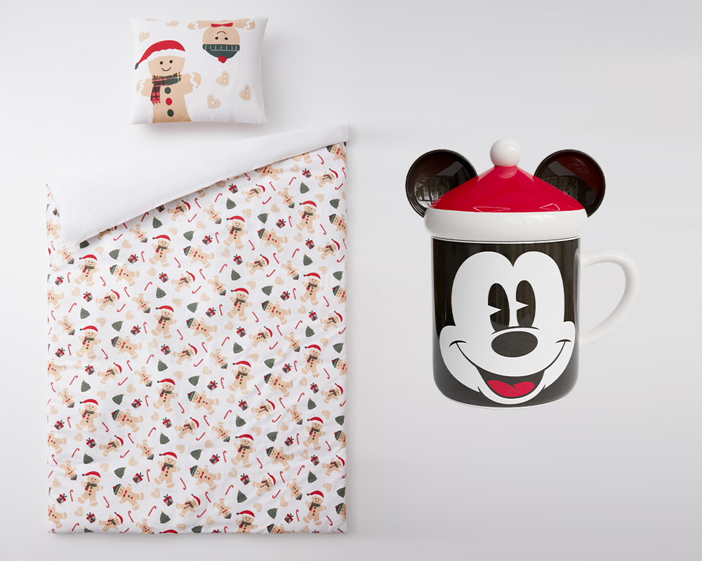 Pepco Ziemassvētku gultasveļa bērna dāvanai blakus Ziemassvētku dāvanu krūzei ar peles Mikija motīvu.