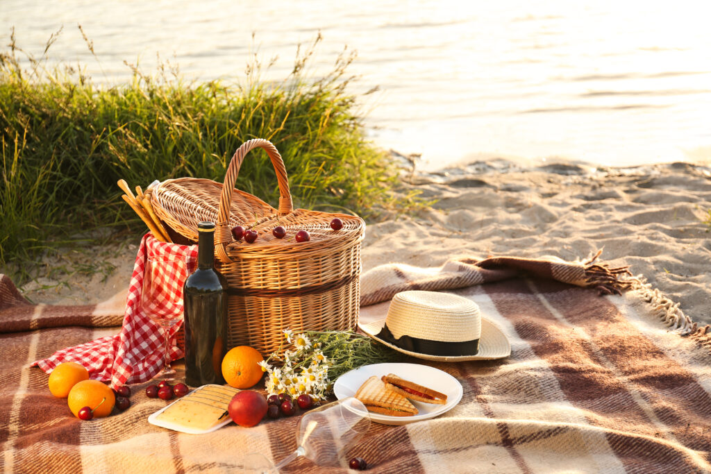 Piknika grozs romantiskām vakariņām pludmalē pie upes.