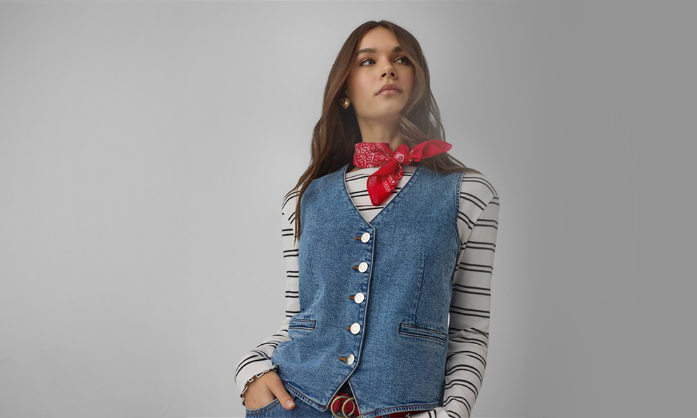 Sieviete valkā zilu džinsa žaketi un sarkanu bandanu ap kaklu.